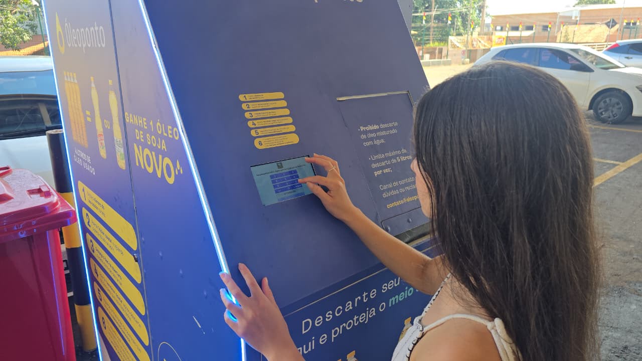 Usuária interagindo com a interface touchscreen da estação Óleoponto